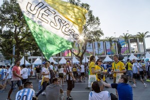 UNDER THE BANNER Southern Baptist student volunteers (right, in yellow shirts) share the Gospel with Argentine soccer fans in front of Rio de Janeiro’s national stadium on June 15 as a bystander walks through the crowd, carrying a banner proclaiming Jesus. Photo © 2014 IMB / Wilson Hunter