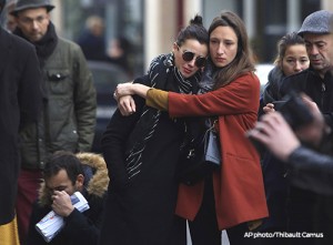 Women comfort each other as they stand in front of the Carillon cafe, in Paris, Saturday, Nov.14, 2015. French President Francois Hollande vowed to attack Islamic State without mercy as the jihadist group admitted responsibility Saturday for orchestrating the deadliest attacks inflicted on France since World War II. (AP Photo/Thibault Camus)