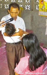 Pastor Lasawang prays at baby dedication. (Photo and caption courtesy of Christian Aid Mission)