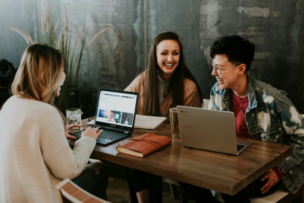 Young people laugh around laptops